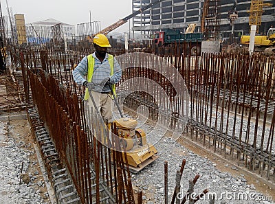 Builder worker at sand ground compaction with vibration plate compactor machine Editorial Stock Photo